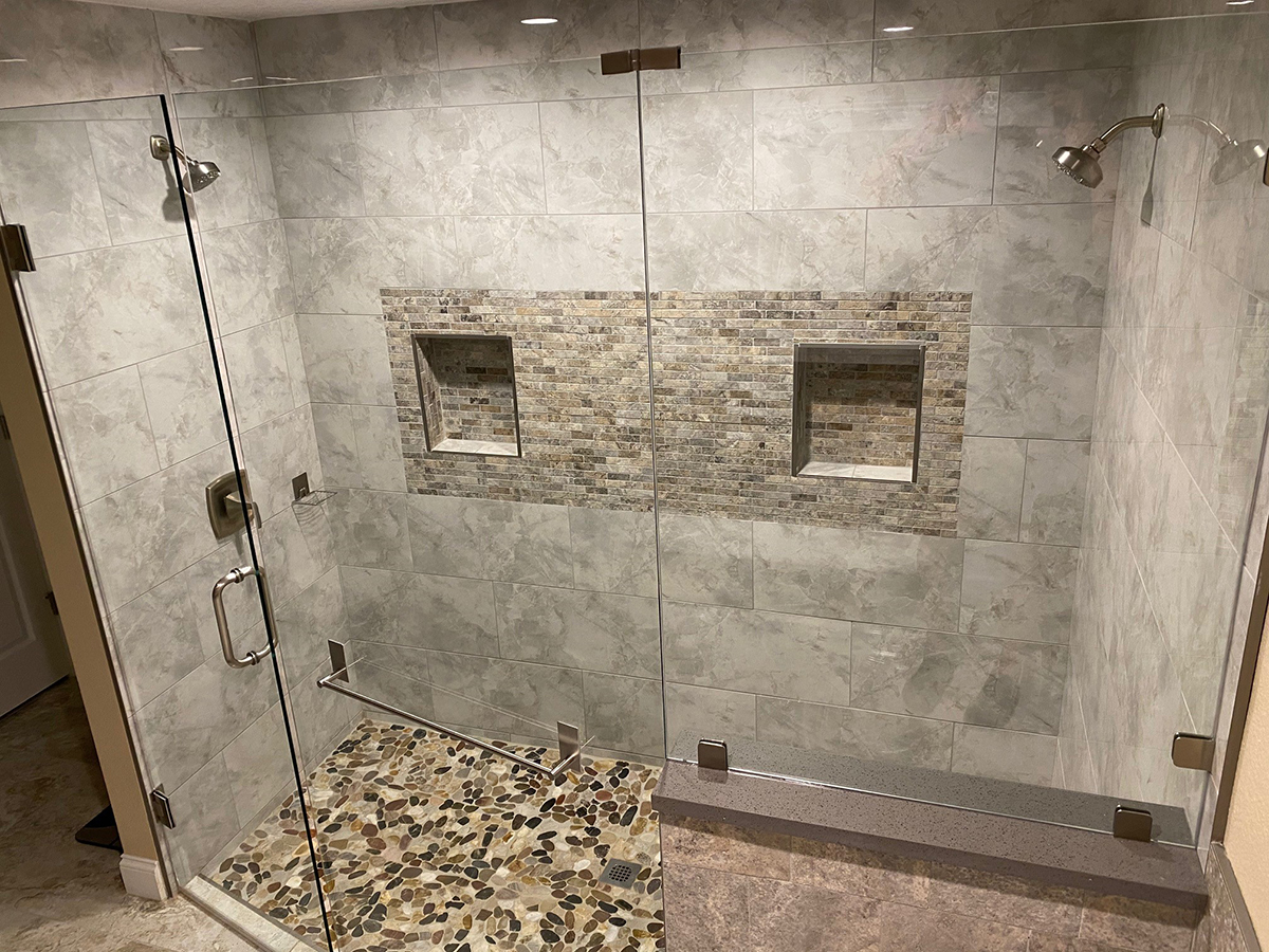 Tiled walk-in shower with glass doors and a pebble-stone floor