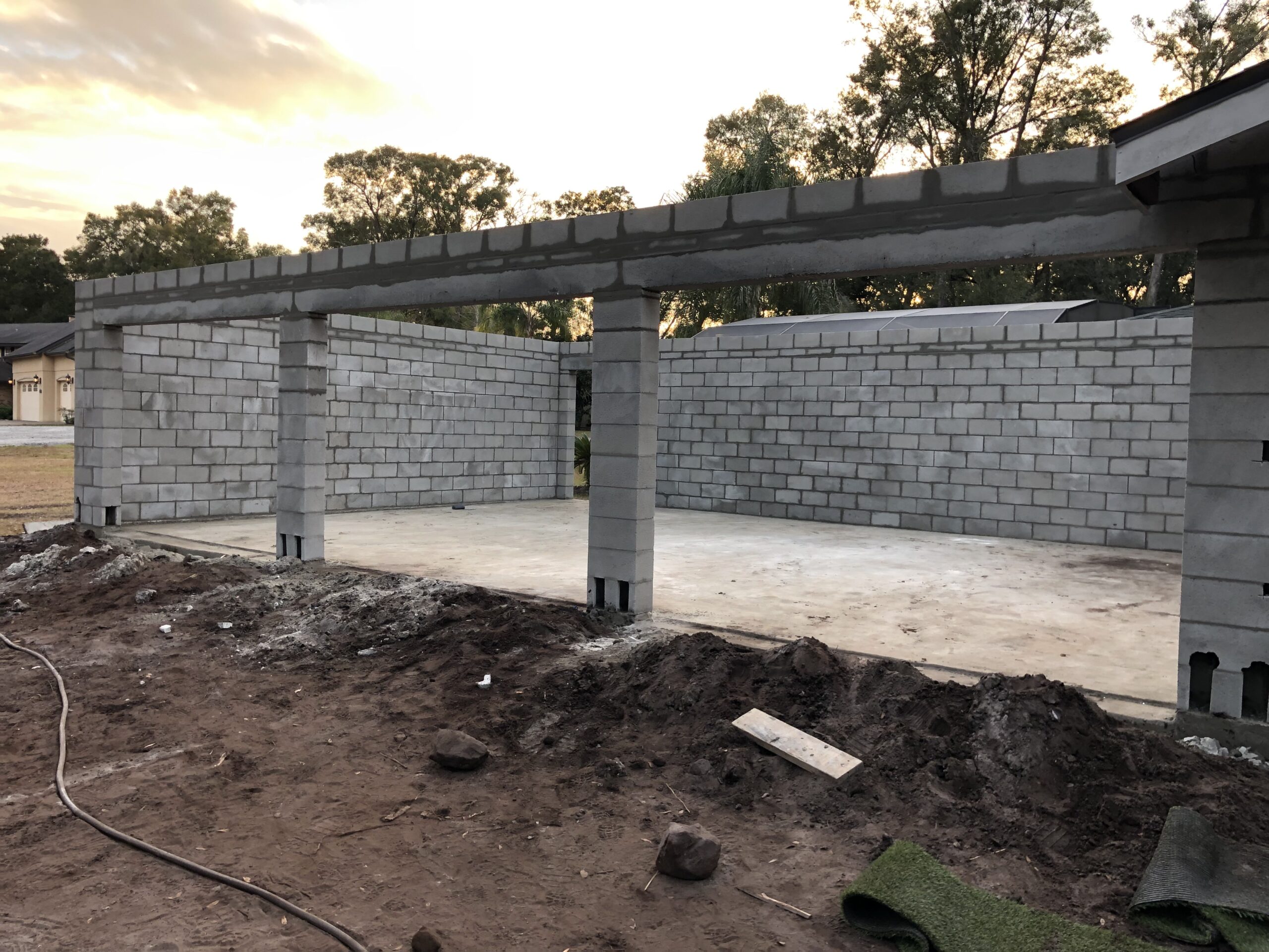 Concrete block carport structure under construction at dusk